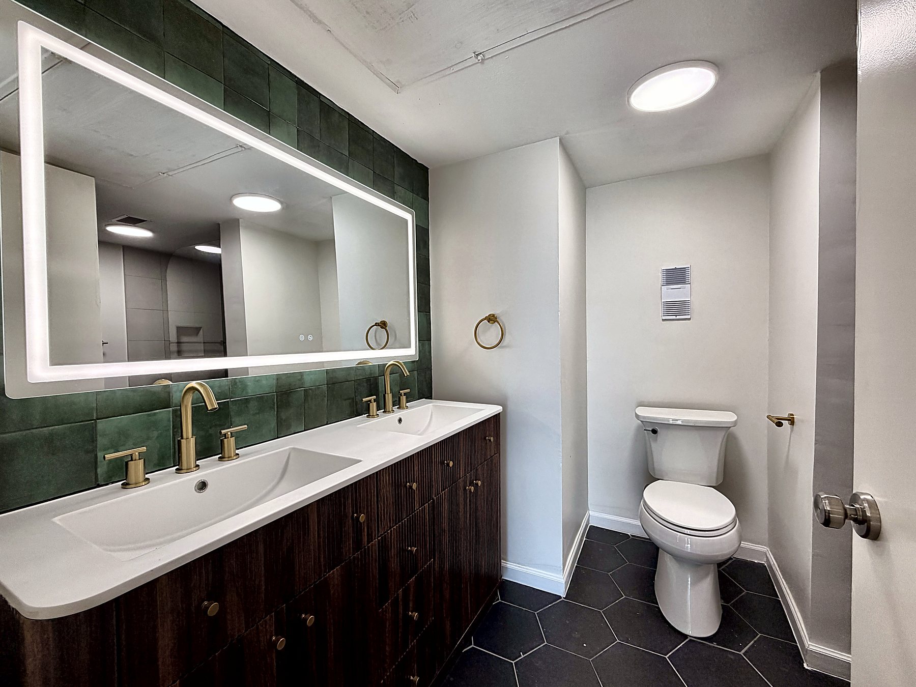 Main bathroom with double vanity, green zellige tile and LED mirror
