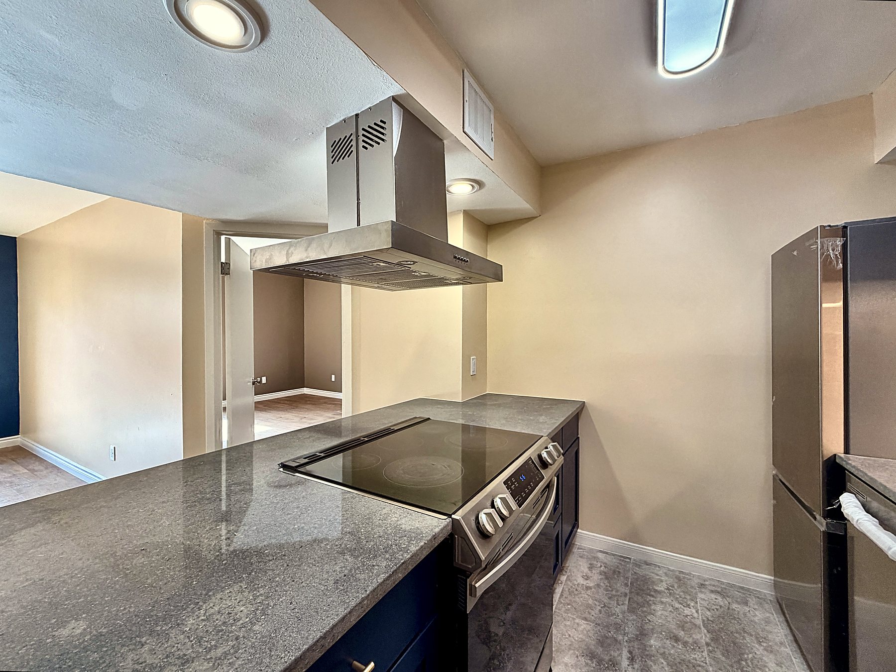 Kitchen pass-through seen from the living room, with island hood and new stainless appliances